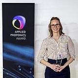 Eine Person hält einen Pokal vom "Applied Photonics Award" in der Hand