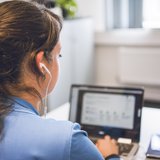 Eine Person sitzt vor einem Laptop auf dem eine Videokonferenz läuft.