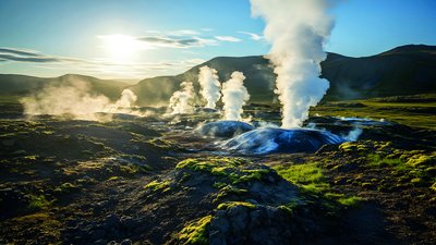 Das Bild zeigt eine grüne Landschaft mit heißen Quellen und erinnert damit an Erdwärme.